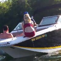 Woman subtly urinating off the side of a boat while talking with her friends